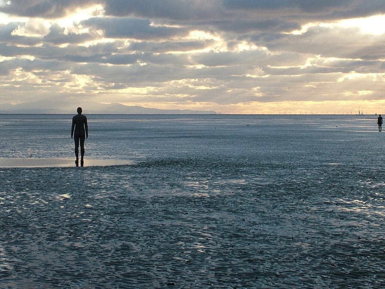 A beach scape with multiple life-size cast-iron moulds of the artists own body
