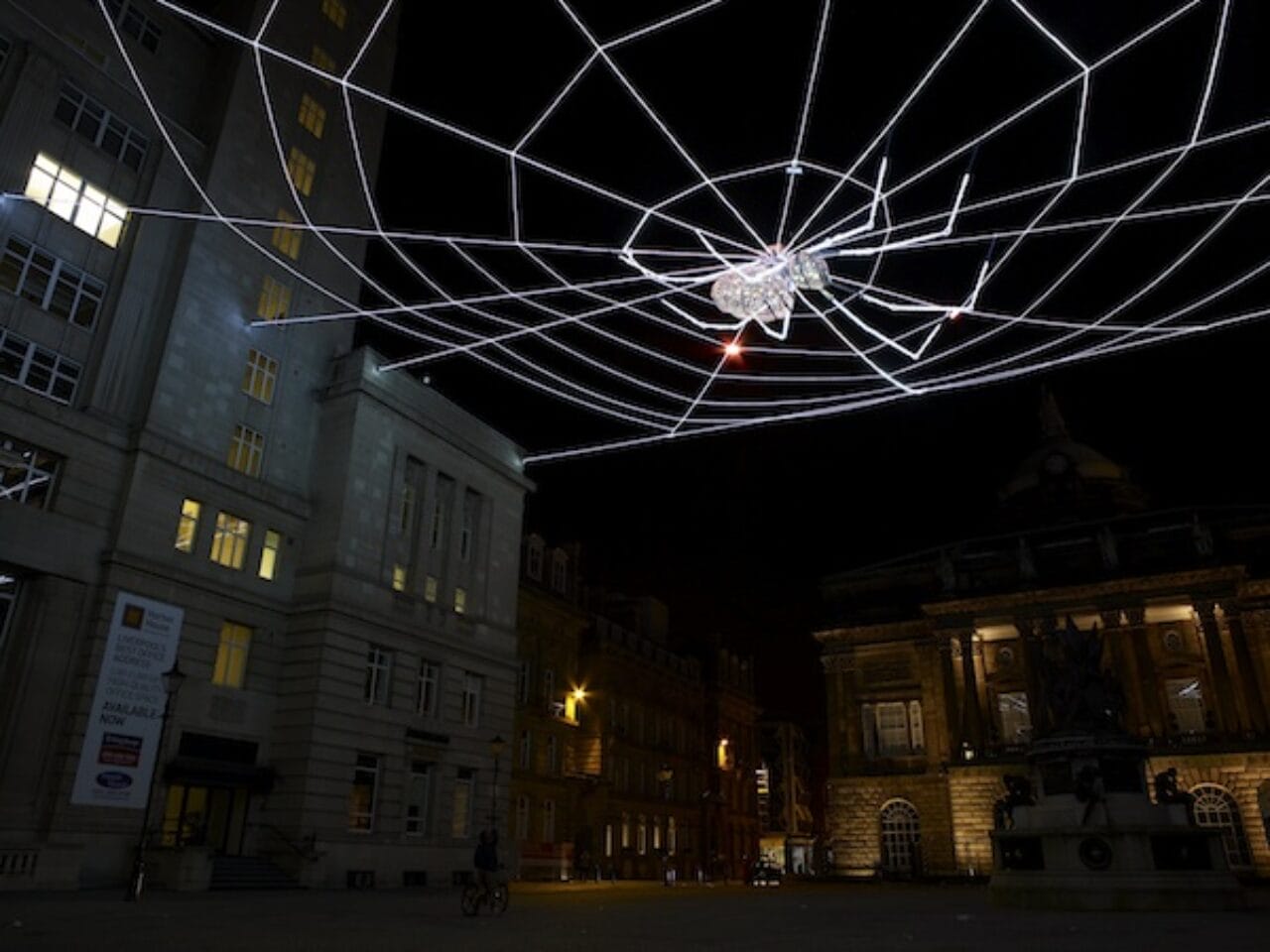 A giant LED lit web hanging above Liverpool's Exchange Flags, with a crystal-studded spider in the center.