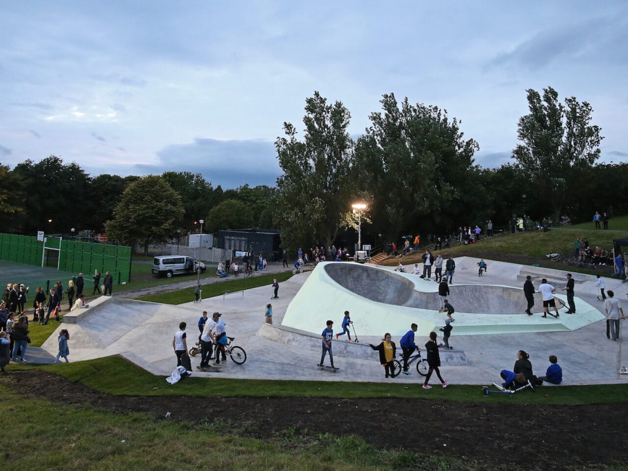 A glow-in-the-dark wheels park surrounded by people standing and people with bikes.