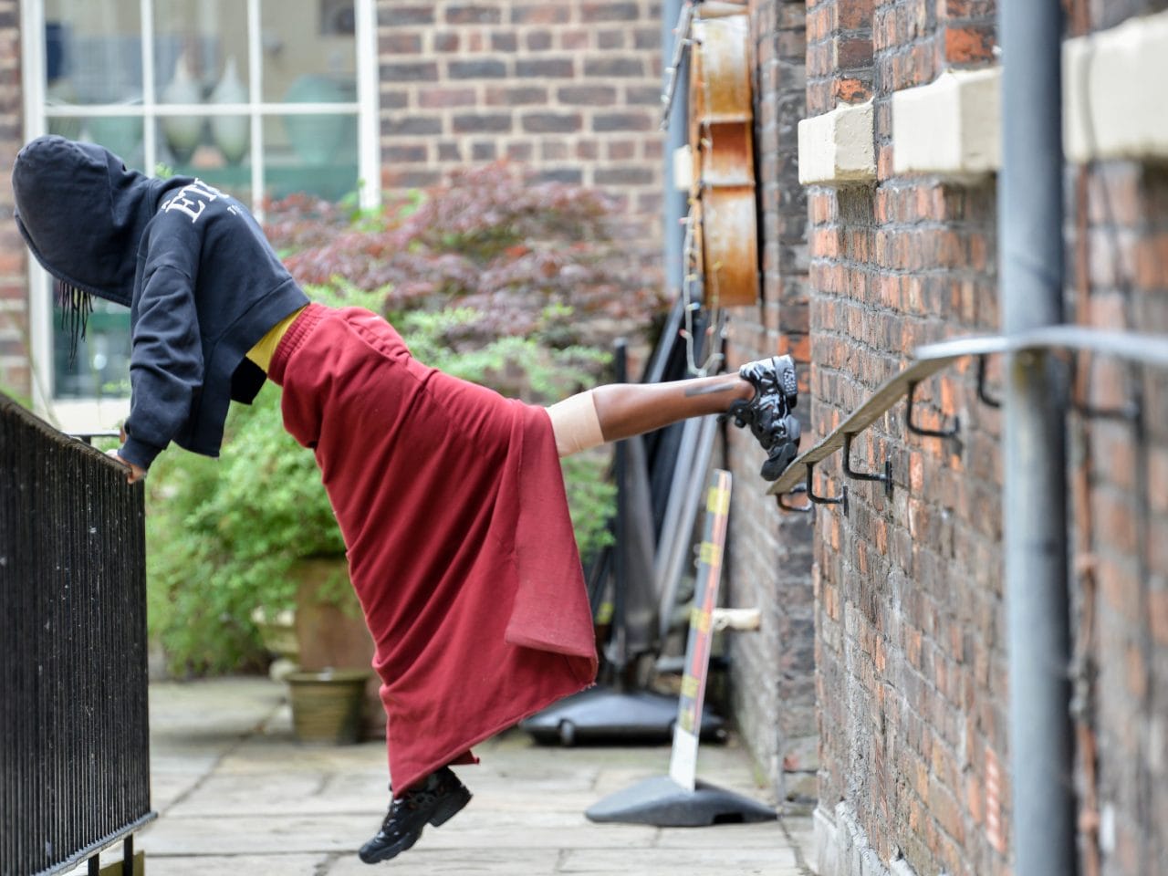 The artist with leaning on a railing with one foot holding them up from the brick wall.