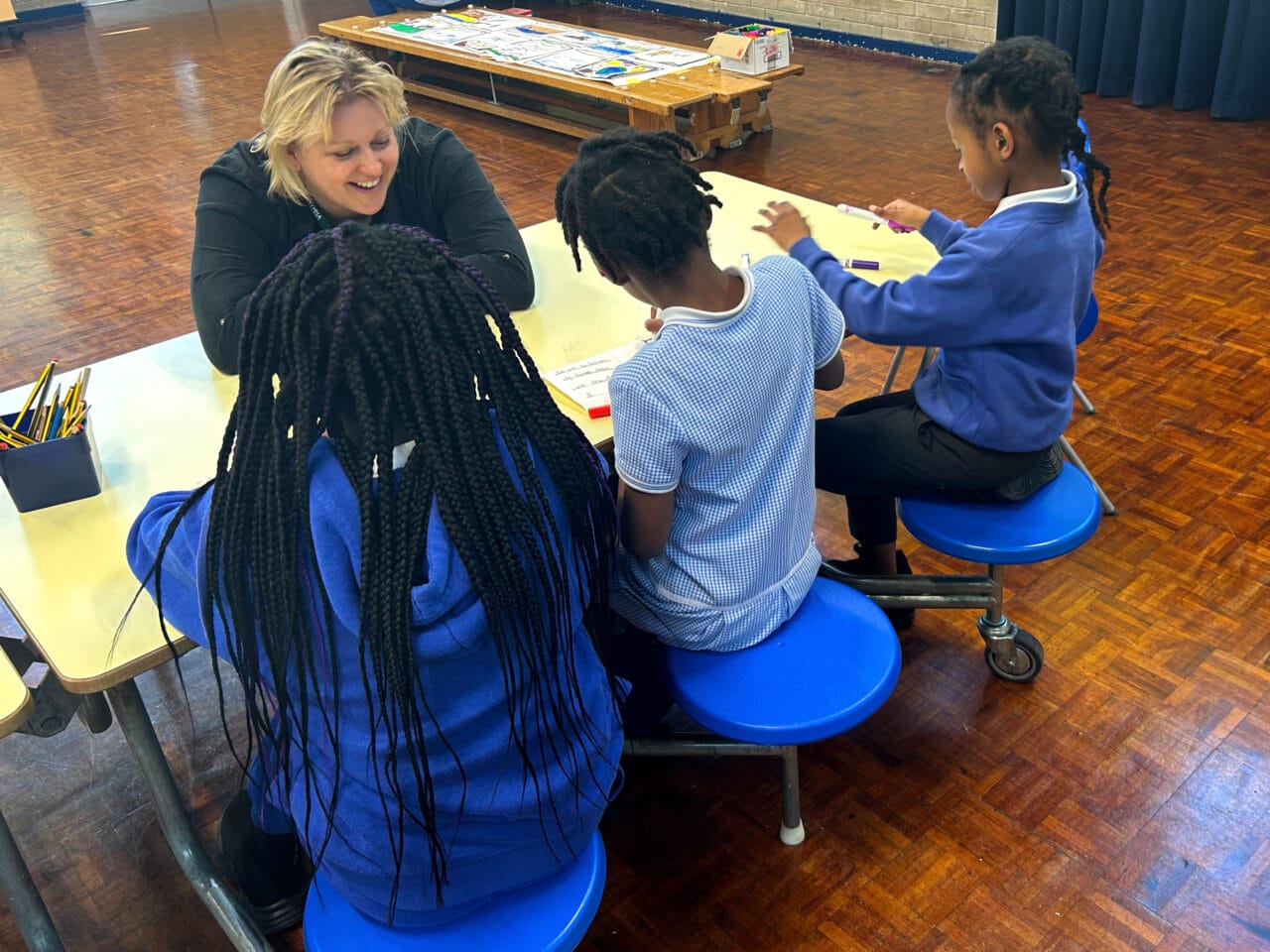 The artist sitting and talking to three children in a workshop