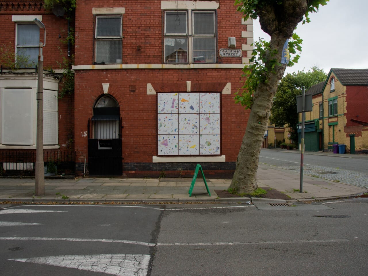 An artwork in a window space with nine white squares with various ceramic embedded pieces.