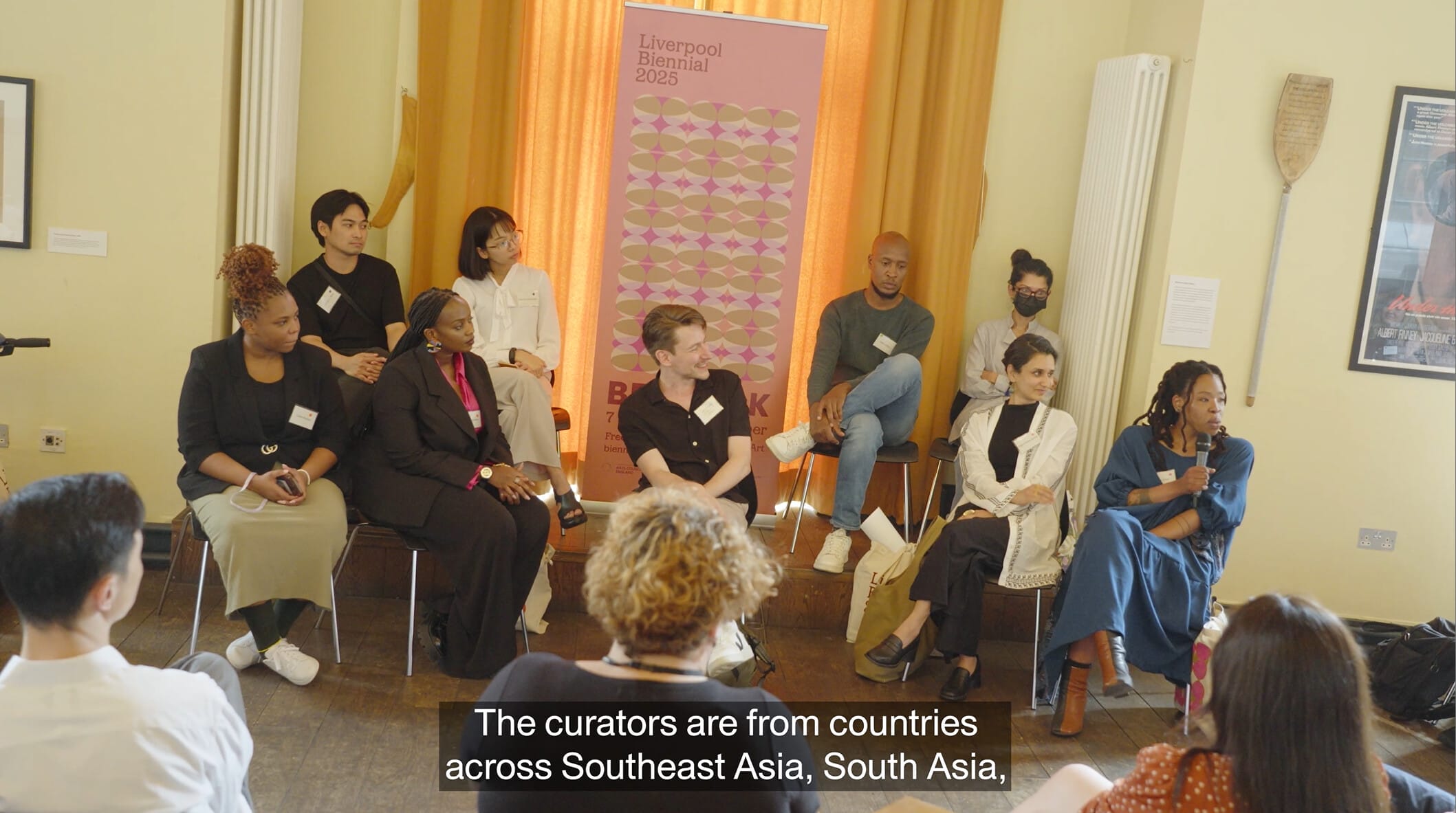 A group of people sat in front of an audience, taking turns to speak